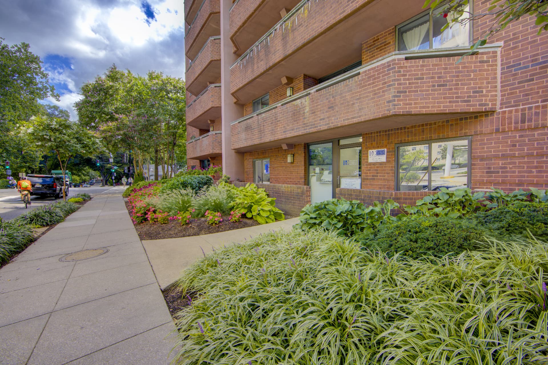 Front of the brick building housing DC Implant & Cosmetic Dentistry on Connecticut Ave NW in Washington, DC, with landscaped entrance